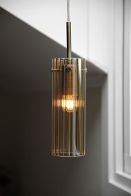 Tibia Ø7 Ámbar/latón lámpara de ventana De Markslöjd - Lámpara cilíndrica de cristal ámbar acanalado con elegantes detalles de latón: un diseño cálido y decorativo que crea una luz suave y ambiental en la ventana.