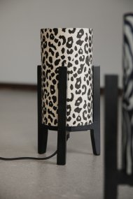 Eruca 34cm Leopardo lámpara de mesa De Markslöjd - La base de madera negra se combina con una pantalla cil&iacute;ndrica de tela con estampado de leopardo en crema y marr&oacute;n, lo que le confiere un estilo moderno y &uacute;nico.