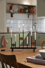 Candelabra 7 Lights Negro De Konstsmide - Las siete velas est&aacute;n enmarcadas por detalles decorativos de vidrio de colores en verde, rojo y &aacute;mbar, creando un ambiente elegante y festivo.