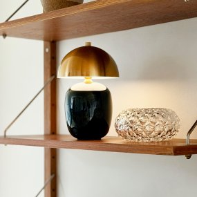 Manhatten 23cm Negro/latón portátil De Dyberg Larsen - La base de cer&aacute;mica negra brillante armoniza elegantemente con la pantalla de metal con acabado de lat&oacute;n oscuro, creando un estilo moderno y atemporal.