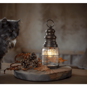 Aina Bronce De Star Trading - Una linterna clásica y elegante de metal y vidrio que emite una luz blanca cálida y acogedora.