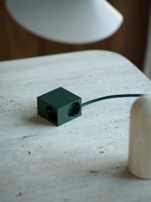 Cuboid Verde oscuro De Kord - Diversas opciones de montaje: Fije el enchufe directamente a superficies met&aacute;licas con los laterales magn&eacute;ticos, utilice el soporte incluido con superficie de fricci&oacute;n para una colocaci&oacute;n estable sobre una mesa o m&oacute;ntelo en la pared con cinta adhesiva 3M para una toma de corriente discreta y de f&aacute;cil acceso.