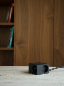 Cuboid Negro De Kord - Diversas opciones de montaje: fije el enchufe directamente a superficies met&aacute;licas con los laterales magn&eacute;ticos, utilice el soporte incluido con superficie de fricci&oacute;n para una colocaci&oacute;n estable sobre una mesa o m&oacute;ntelo en la pared con cinta adhesiva 3M para una toma de corriente discreta y de f&aacute;cil acceso.