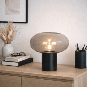 Alba 32cm Negro/Ahumado lámpara de mesa De Nordic Lighting - Su base de metal negro le confiere estabilidad y un aspecto sofisticado, mientras que la pantalla de cristal ahumado crea una luz suave y acogedora.