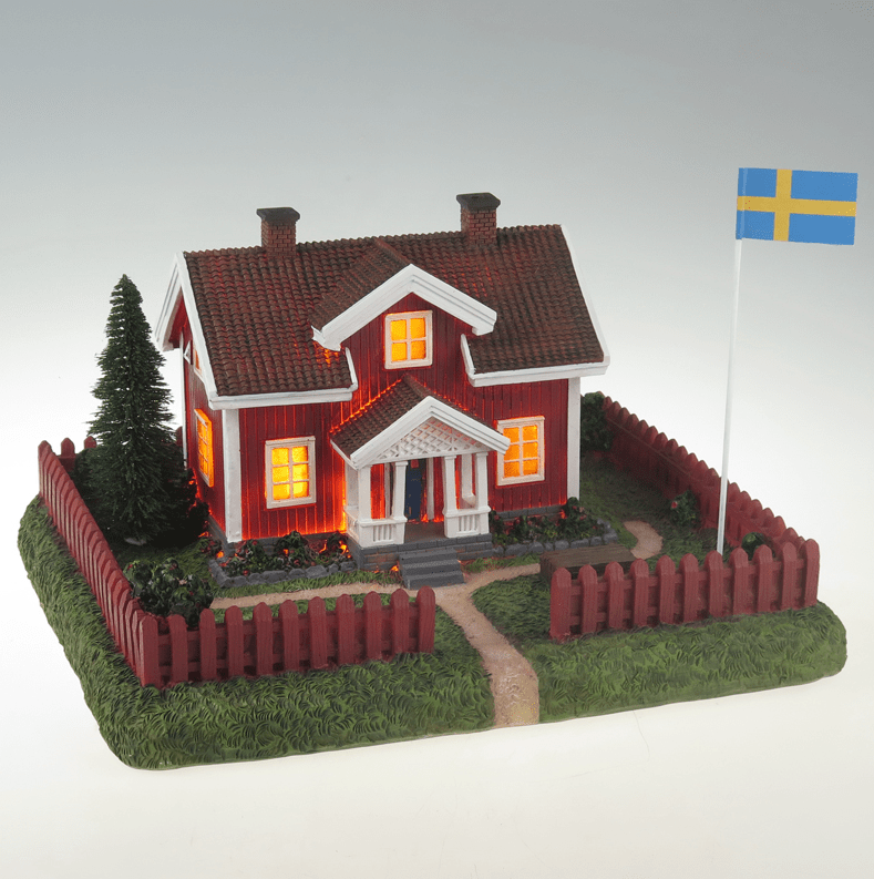 Sommarby ROJO De Pixie Design - "La cabaña roja en verano" es una lámpara de cerámica decorativa que representa una clásica casa de verano sueca con un jardín circundante y un asta de bandera.