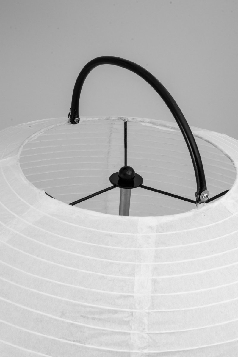 Osaka Blanco lámpara de pie De Globen Lighting - La lámpara está hecha de papel de arroz blanco y tiene un mango decorativo de metal pintado en negro mate y un soporte a juego en la parte inferior sobre el que descansa la pantalla de papel.