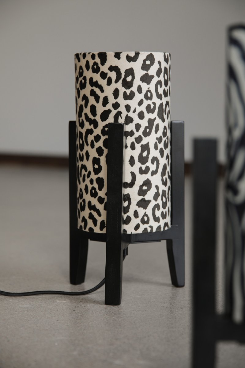 Eruca 34cm Leopardo lámpara de mesa De Markslöjd - La base de madera negra se combina con una pantalla cil&iacute;ndrica de tela con estampado de leopardo en crema y marr&oacute;n, lo que le confiere un estilo moderno y &uacute;nico.