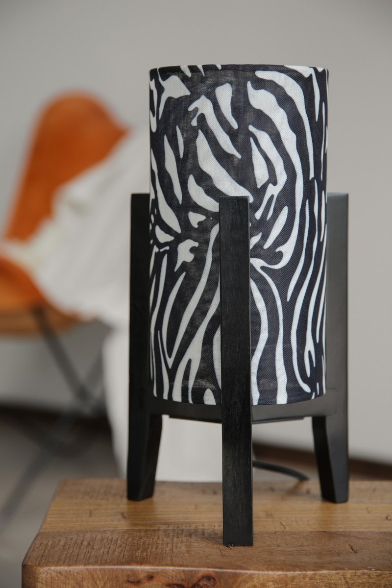 Eruca 34cm Cebra lámpara de mesa De Markslöjd - La base de madera negra armoniza a la perfecci&oacute;n con la pantalla cil&iacute;ndrica de tela con estampado de cebra en blanco y negro, otorg&aacute;ndole a la l&aacute;mpara un car&aacute;cter gr&aacute;fico y expresivo.