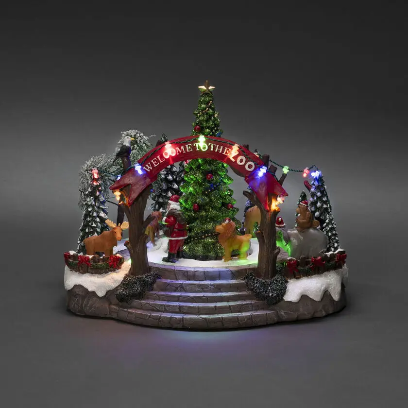 Decoración Navideña Mecánica Con Zoológico 20cm Multicolor De Konstsmide - Esta decoraci&oacute;n navide&ntilde;a mec&aacute;nica presenta una escena colorida con 19 luces LED de color blanco c&aacute;lido, m&uacute;sica, animales y Pap&aacute; Noel alrededor de un &aacute;rbol de Navidad brillante.