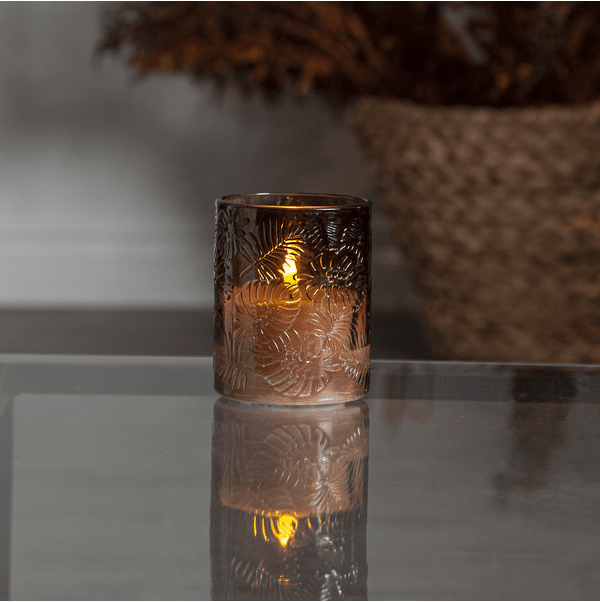 LED Vela Flamme Leaf Marrón De Star Trading - Flamme Leaf es una linterna de cristal que funciona a pilas y está hecha de cristal marrón con un dibujo de hojas en relieve alrededor de una vela de cera blanca.