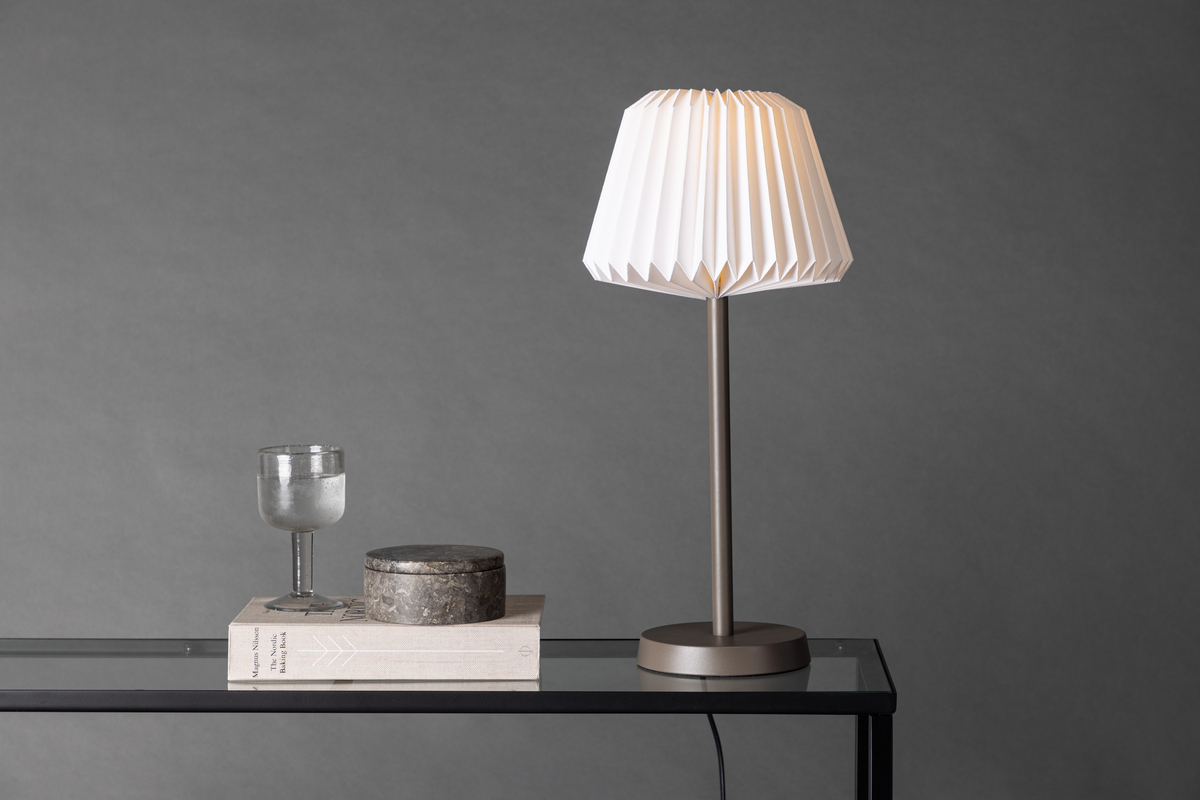 Tandådalen 50cm Marrón oscuro lámpara de mesa De Venture Design - Con un portal&aacute;mparas de acero marr&oacute;n oscuro y una pantalla de papel blanco plisado, esta l&aacute;mpara a&ntilde;ade un toque de dise&ntilde;o sofisticado a tu interior.