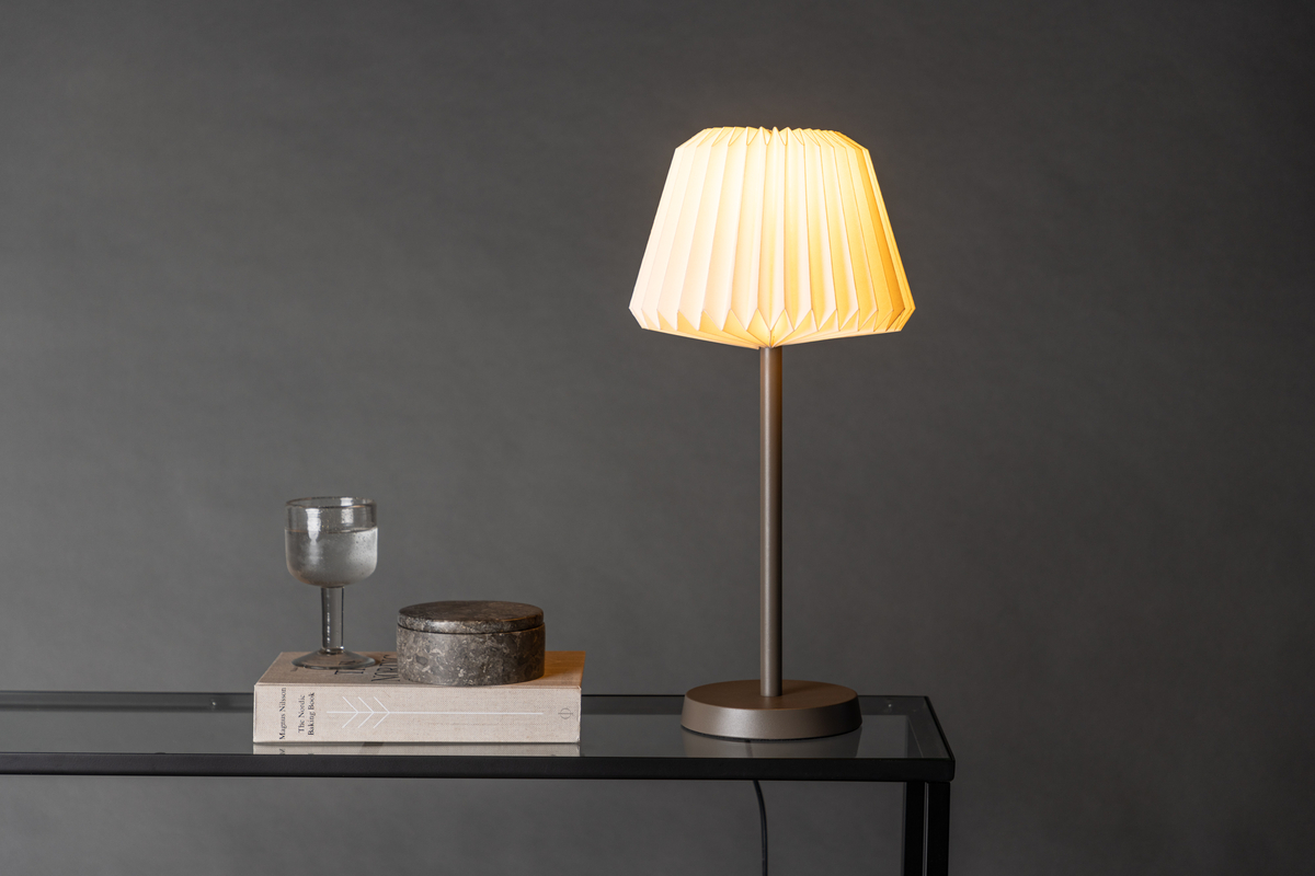 Tandådalen 50cm Marrón oscuro lámpara de mesa De Venture Design - Con un portal&aacute;mparas de acero marr&oacute;n oscuro y una pantalla de papel blanco plisado, esta l&aacute;mpara a&ntilde;ade un toque de dise&ntilde;o sofisticado a tu interior.