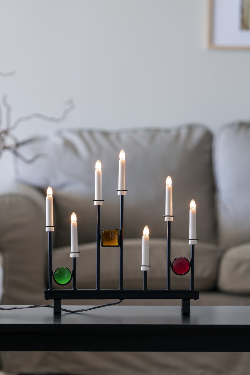 Candelabra 7 Lights Negro De Konstsmide - Las siete velas est&aacute;n enmarcadas por detalles decorativos de vidrio de colores en verde, rojo y &aacute;mbar, creando un ambiente elegante y festivo.