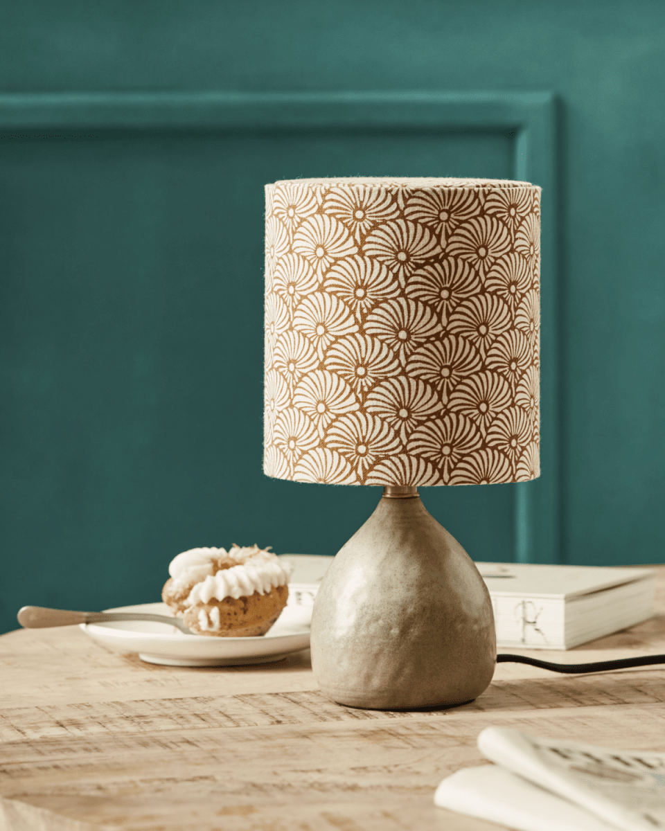 Flores 30cm Arena lámpara de mesa De House Doctor - Cuenta con una base de cerámica color arena y una pantalla de lino decorada con motivos de plumas de sol marrones y arena impresos a mano, equilibrando maravillosamente una estética moderna y acogedora.