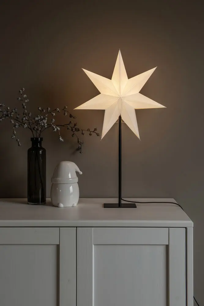 Estrella De Papel Ø40 Blanco De Konstsmide - La elegante estrella blanca reposa sobre un elegante soporte de metal negro y emite una luz suave y agradable.