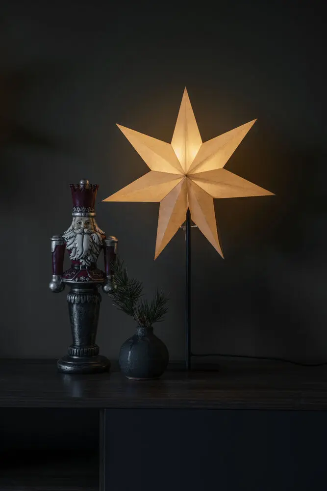 Estrella De Papel Ø40 Beige De Konstsmide - La elegante estrella beige reposa sobre un sencillo soporte de metal negro y emite una luz suave y agradable.