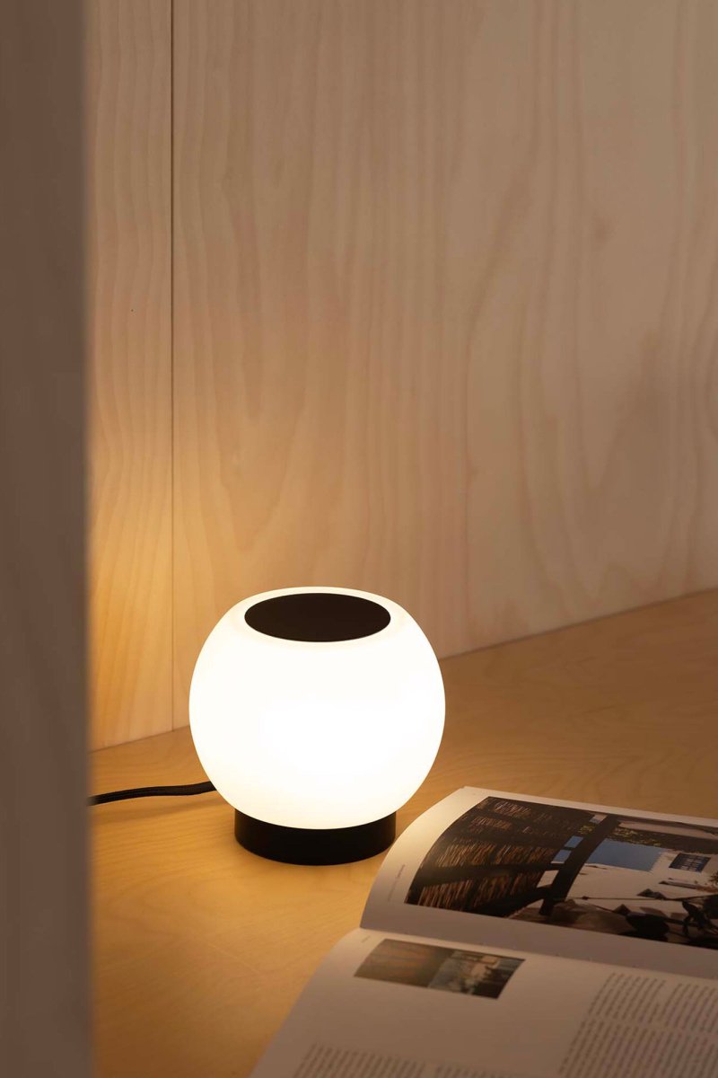 Moy 13cm Negro lámpara de mesa De Faro Barcelona - Moy es una elegante l&aacute;mpara de mesa redonda de acero negro y cristal blanco que proporciona una luz uniforme y agradable, perfecta para salones y espacios p&uacute;blicos.