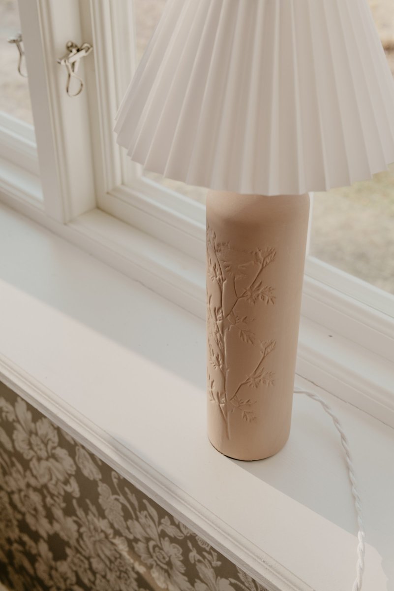 Flora 46cm Lodo lámpara de mesa De Globen Lighting - Como bello detalle, un dibujo de flor de endrino est&aacute; prensado en un lado de la base de la l&aacute;mpara, d&aacute;ndole un verdadero toque de artesan&iacute;a.