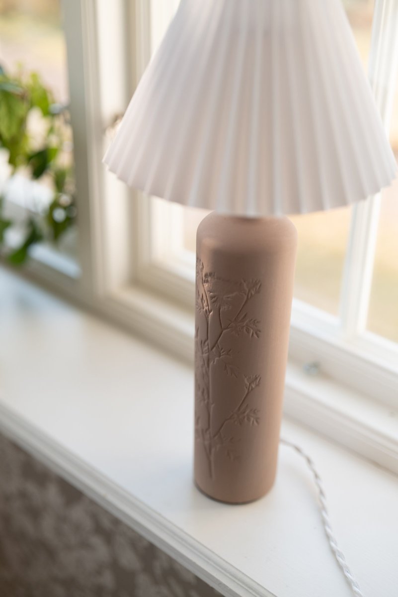 Flora 46cm Lodo lámpara de mesa De Globen Lighting - Como bello detalle, un dibujo de flor de endrino est&aacute; prensado en un lado de la base de la l&aacute;mpara, d&aacute;ndole un verdadero toque de artesan&iacute;a.