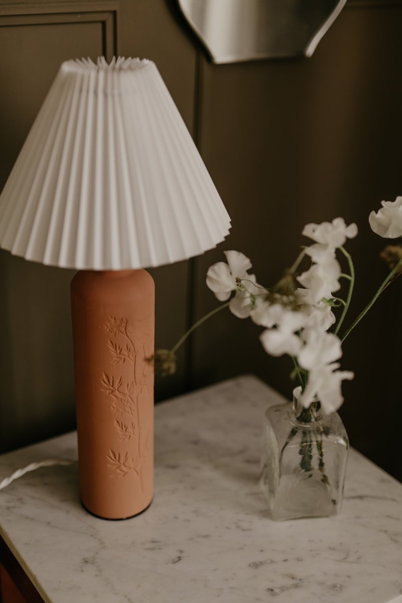 Flora 46cm Terracota lámpara de mesa De Globen Lighting - La base de la l&aacute;mpara est&aacute; hecha de cer&aacute;mica de color terracota y tiene una pantalla textil plisada de color crema.