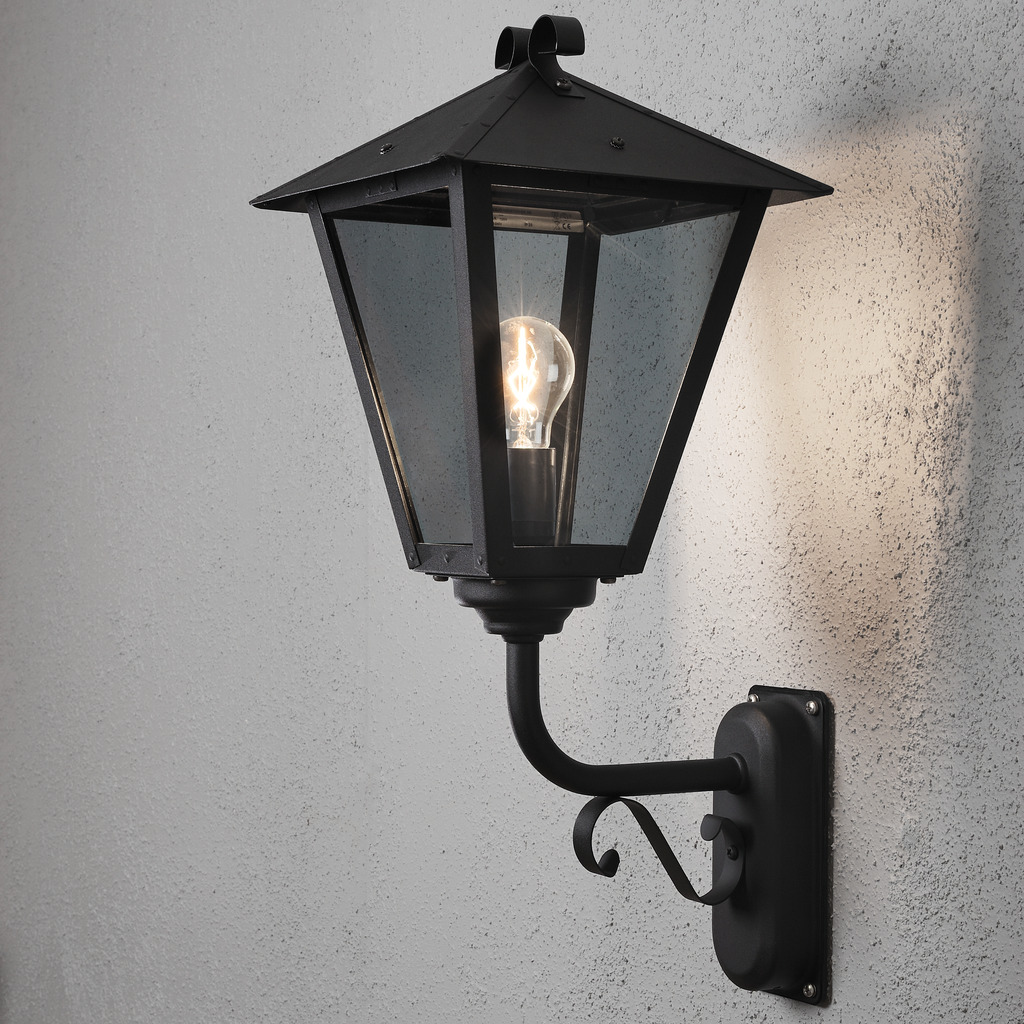 Benu Negro lámpara de exterior De Konstsmide - La forma cl&aacute;sica de linterna y los materiales robustos hacen de esta l&aacute;mpara la elecci&oacute;n perfecta para cualquiera que quiera crear un ambiente acogedor en zonas de entrada o pasillos largos.