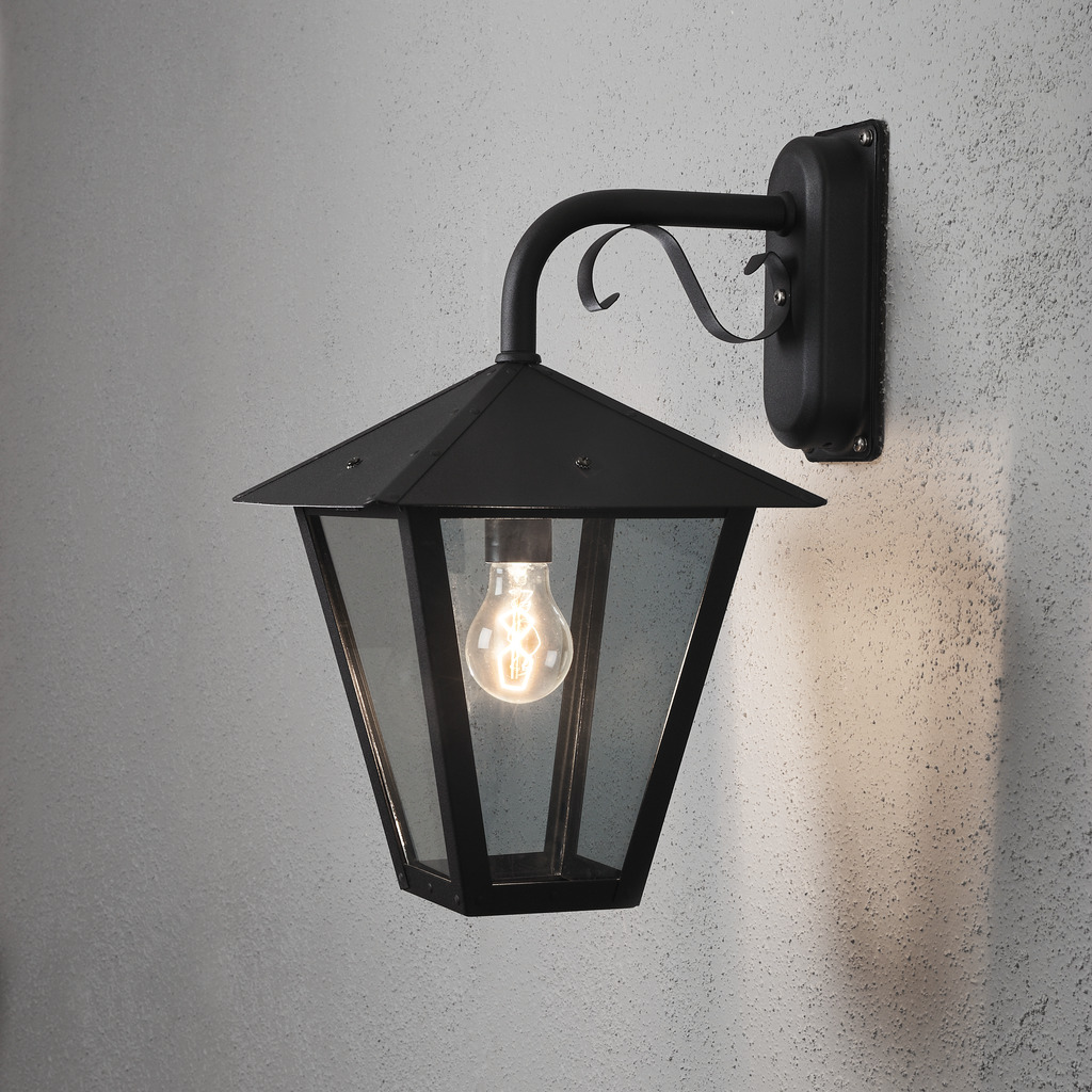 Benu Negro lámpara de exterior De Konstsmide - La forma cl&aacute;sica de linterna y los materiales robustos hacen de esta l&aacute;mpara la elecci&oacute;n perfecta para cualquiera que quiera crear un ambiente acogedor en zonas de entrada o pasillos largos.