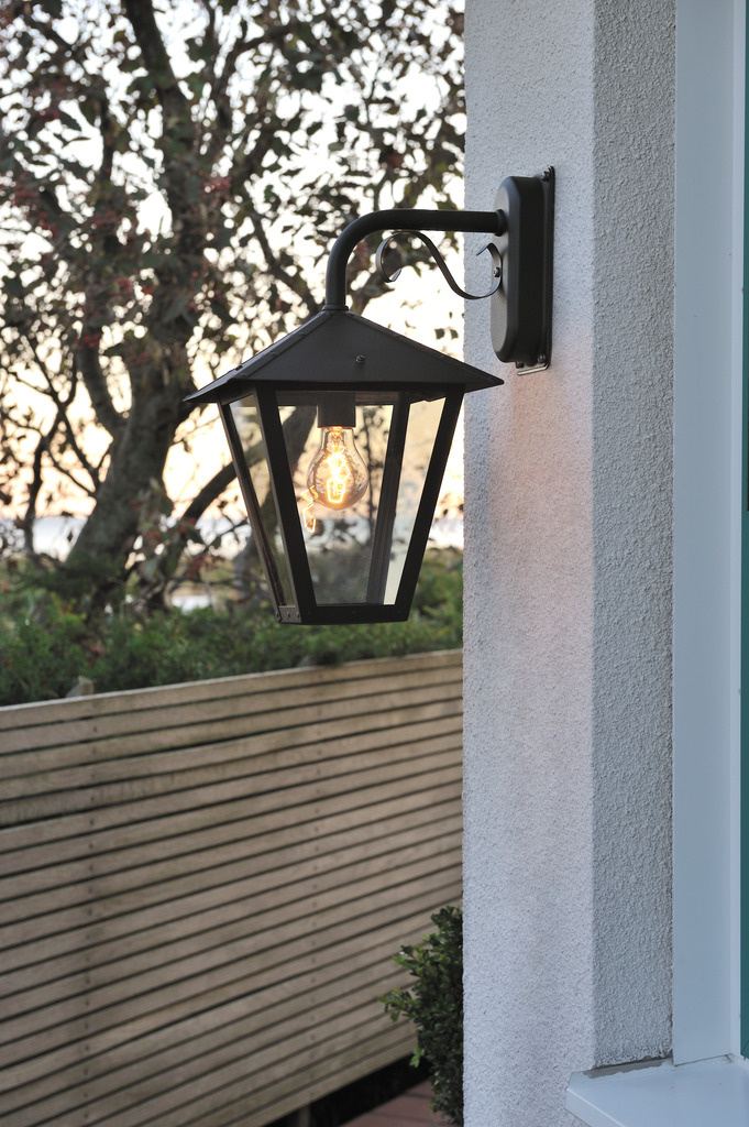 Benu Negro lámpara de exterior De Konstsmide - La forma cl&aacute;sica de linterna y los materiales robustos hacen de esta l&aacute;mpara la elecci&oacute;n perfecta para cualquiera que quiera crear un ambiente acogedor en zonas de entrada o pasillos largos.