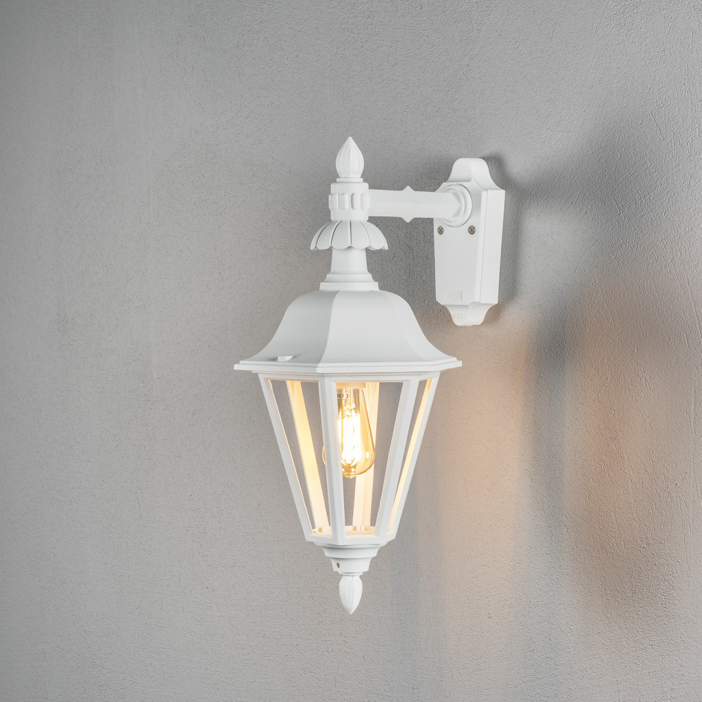 Pallas Blanco lámpara de exterior De Konstsmide - Con su diseño en forma de linterna y paneles de vidrio transparente, la lámpara emite una luz cálida y acogedora que es perfecta para entradas, patios y pasillos.