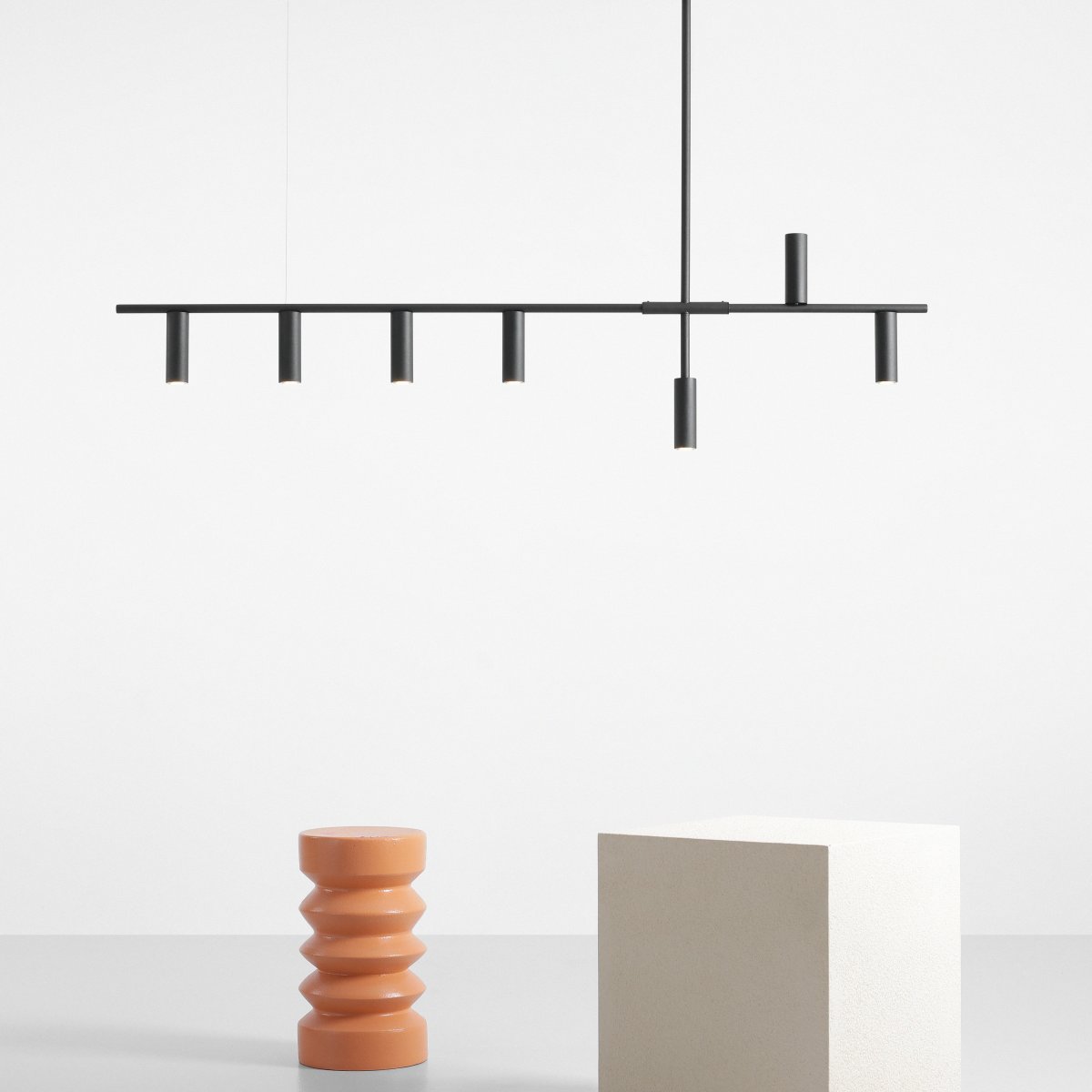 Trevo 145cm Negro Lámpas de techo De Artera - Trevo, con un acabado negro mate, es una lámpara de techo minimalista que distribuye la luz a través de seis fuentes de luz orientadas hacia abajo, mientras que un solo tubo dirige la luz hacia arriba para romper el patrón.