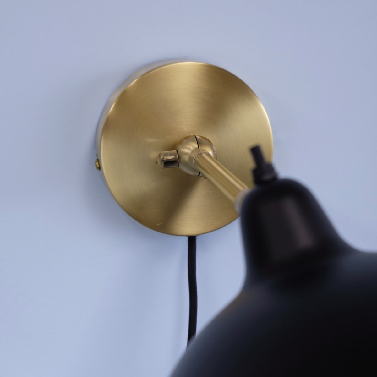 Futura 43cm Latón lámpara de pared De Dyberg Larsen - Está hecho de metal con un exterior negro y un interior de latón, lo que le da un aspecto elegante.