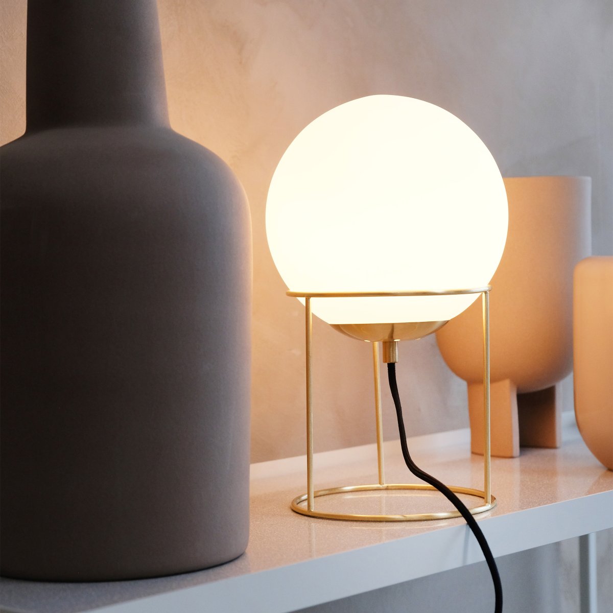 Madrid 34cm Latón lámpara de mesa De Dyberg Larsen - Madrid es una lámpara de mesa moderna que combina elegancia y sencillez con su pantalla redonda de cristal blanco opalino y su elegante marco de latón.