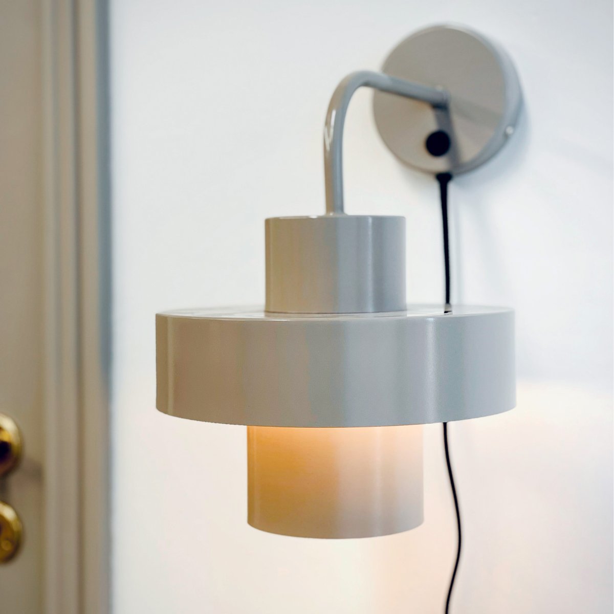 Stoke Ø15 Gris cálido lámpara de pared De Dyberg Larsen - La lámpara funciona como un elegante detalle de decoración y como fuente de luz y tiene un interruptor de encendido en la base.