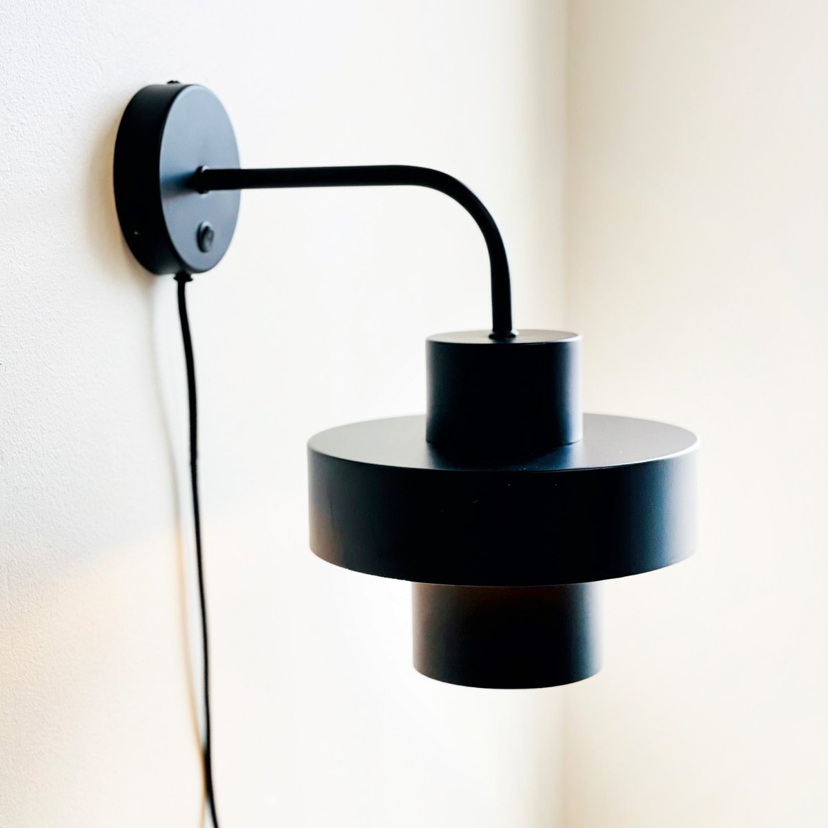 Stoke Ø15 Negro lámpara de pared De Dyberg Larsen - La lámpara funciona como un elegante detalle de decoración y como fuente de luz y tiene un interruptor de encendido en la base.
