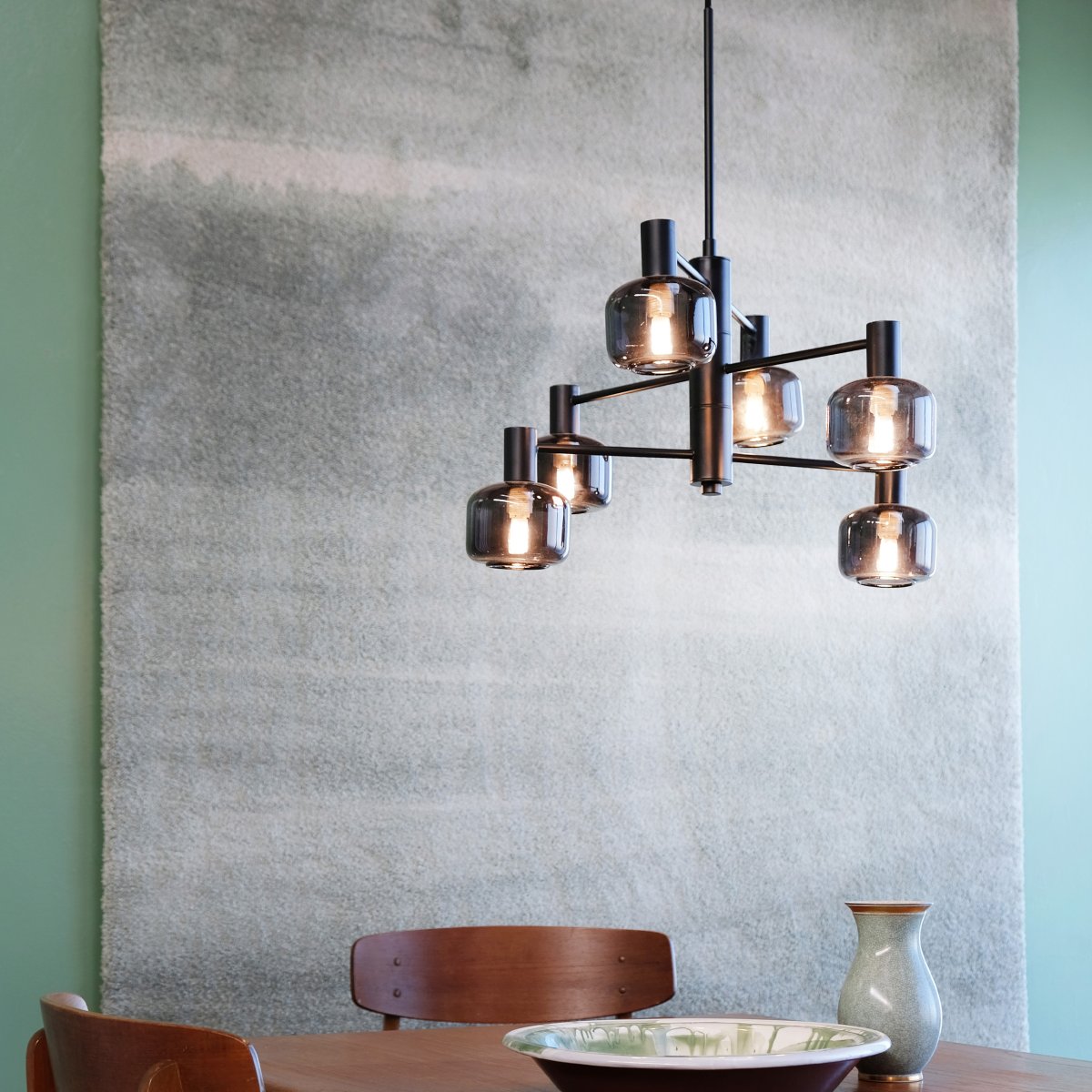 Arp Ø50 Negro Lámpas de techo De Dyberg Larsen - Cree el equilibrio perfecto entre forma y función con la lámpara de araña Arp, que cuenta con 6 hermosas pantallas de vidrio ahumado y una elegante suspensión negra.