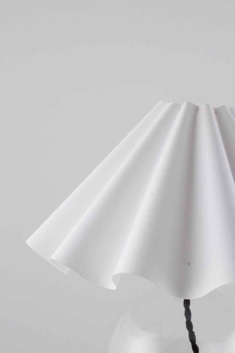 Judith 28cm Claro lámpara de mesa De Globen Lighting - La base de la lámpara está hecha de vidrio transparente y tiene un portalámparas de metal negro que combina con el cable negro.