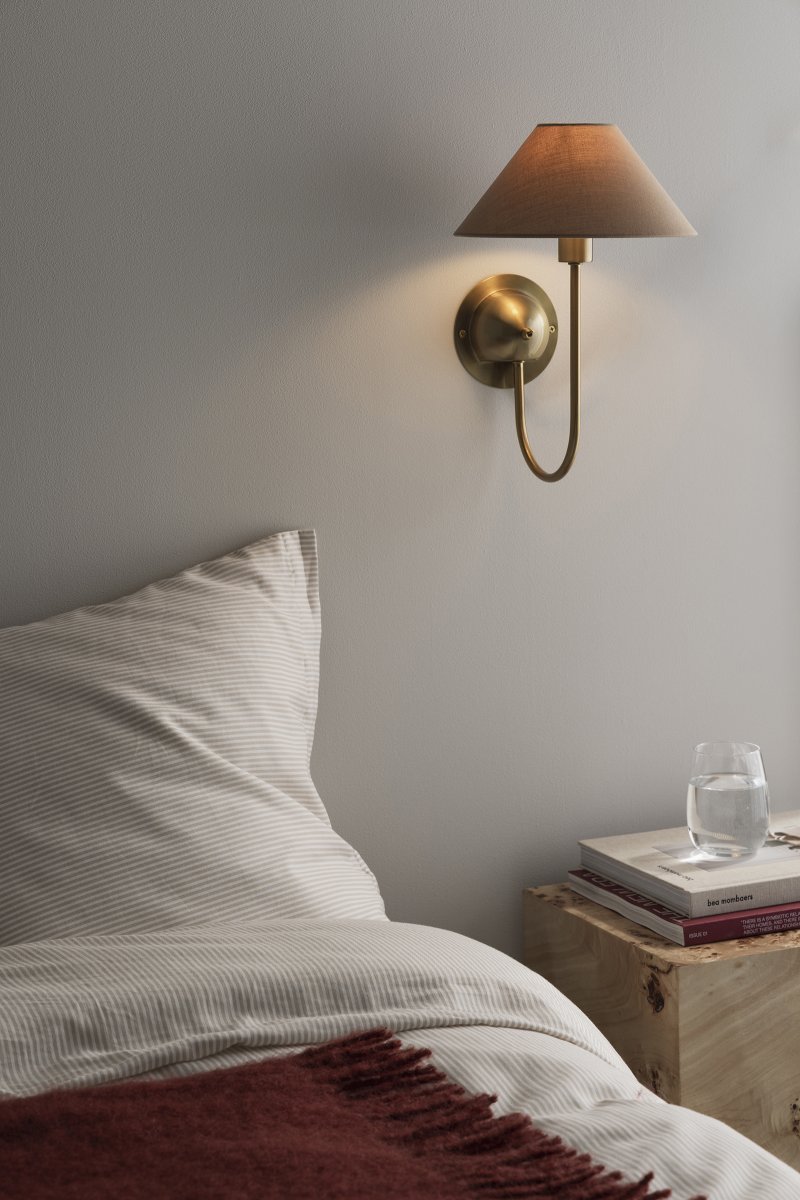 Iris 32cm Latón/marrón lámpara de pared De Globen Lighting - Su brazo ligeramente curvado armoniza a la perfección con la pantalla de tela marrón, dándole a la lámpara un aspecto cálido y clásico.