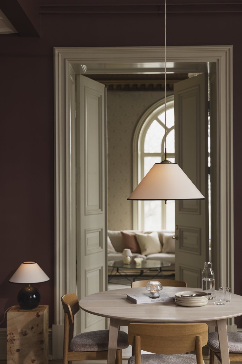 Iris Ø50 Blanco cremoso Lámpas de techo De Globen Lighting - La elegante lámpara colgante Iris, fabricada en hierro con acabado de latón y con una pantalla de algodón color crema hecha a mano, cautiva por su diseño clásico y sus detalles decorativos de latón, convirtiéndola en un impresionante elemento central, por ejemplo, sobre una mesa de comedor.