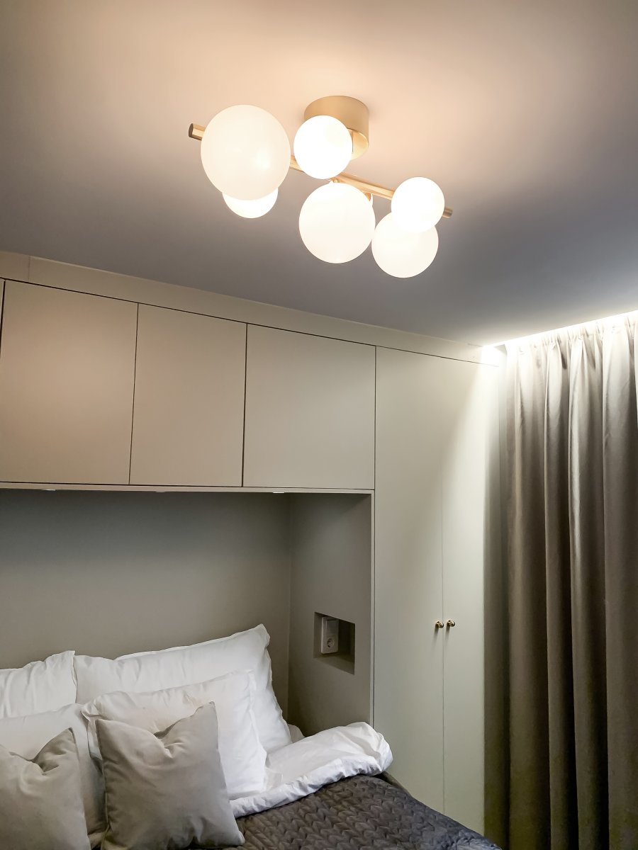 Molekyl 58cm Latón mate plafón De Aneta Lighting - Lámpara de techo de moda de Molekyl en latón mate con 7 pantallas de cristal blanco opal de diferentes tamaños, montadas en una barra de 58 cm de largo.