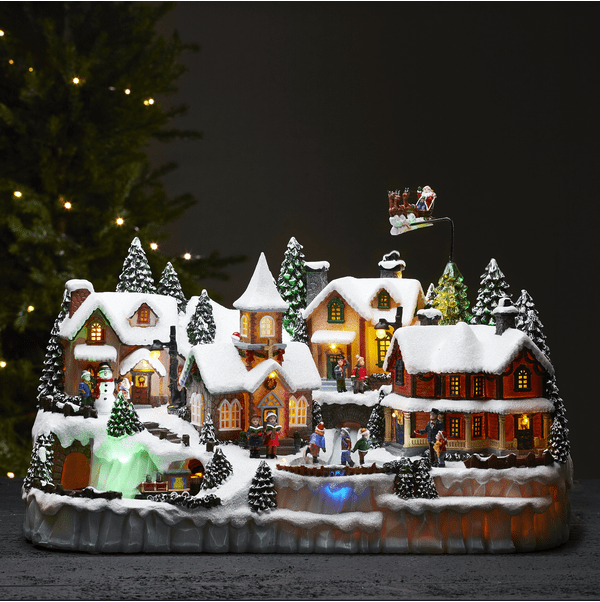 Largeville Multicolor De Star Trading - Adorno navide&ntilde;o grande y detallado con forma de pueblo, con tres piezas giratorias: un tren, ni&ntilde;os patinando sobre hielo, un reno con trineo y Pap&aacute; Noel.