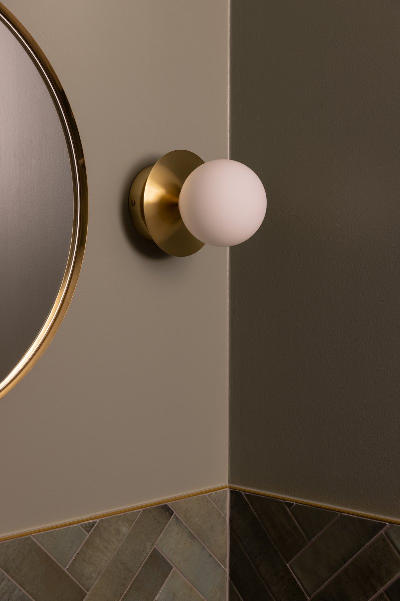 Art Deco Ø16 Latón cepillado/blanco lámpara de baño De Globen Lighting - La l&aacute;mpara est&aacute; hecha de metal y su pantalla de vidrio blanco crea una hermosa iluminaci&oacute;n en la habitaci&oacute;n.