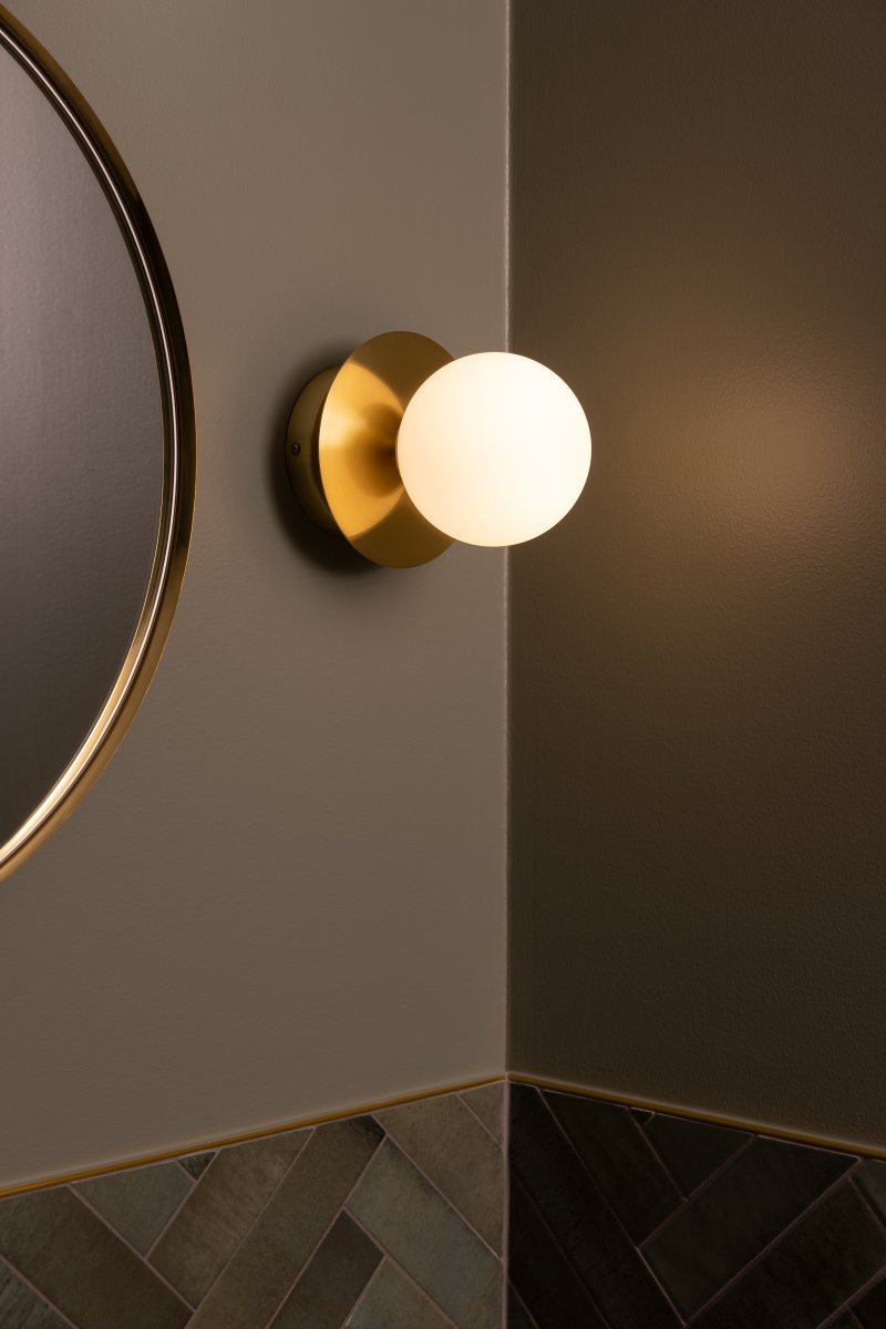 Art Deco Ø16 Latón cepillado/blanco lámpara de baño De Globen Lighting - La l&aacute;mpara est&aacute; hecha de metal y su pantalla de vidrio blanco crea una hermosa iluminaci&oacute;n en la habitaci&oacute;n.