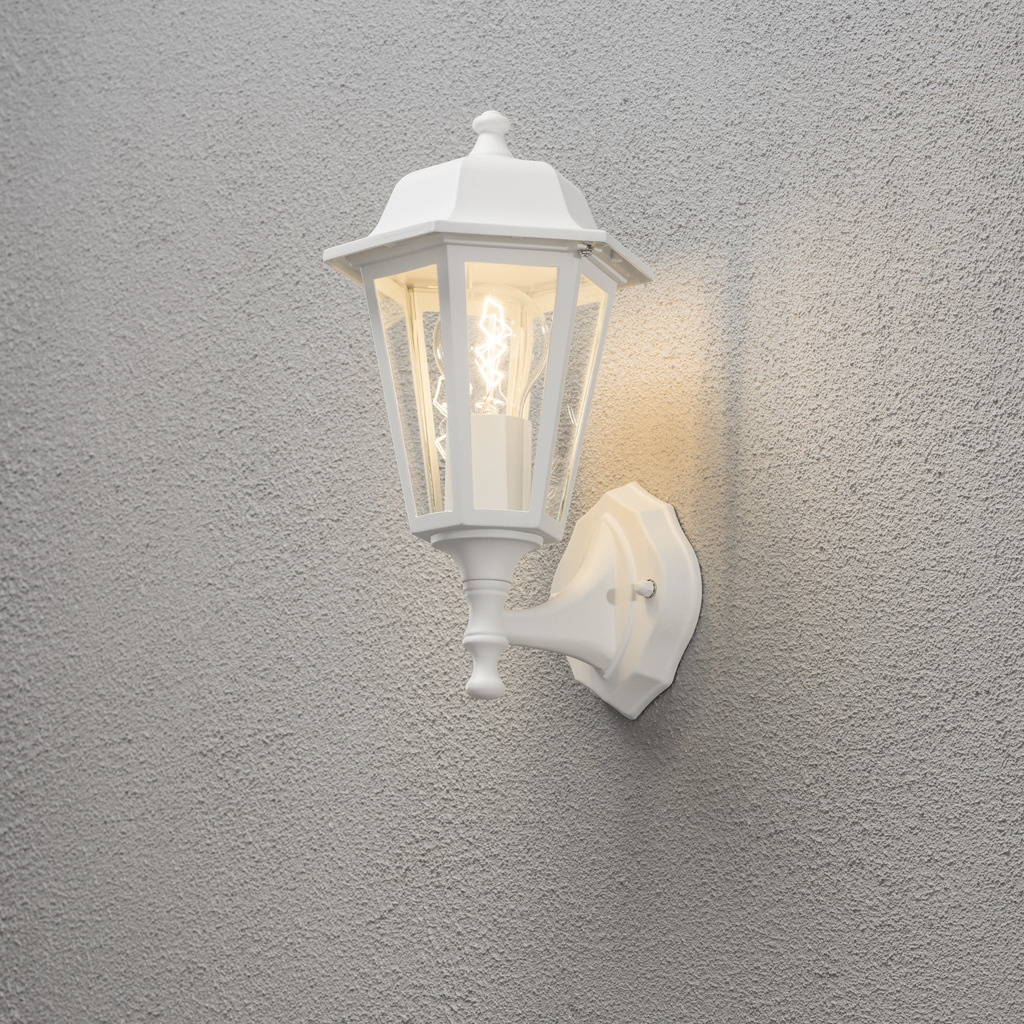 Vägglykta Blanco lámpara de exterior De Konstsmide - Con su diseño en forma de linterna y paneles de vidrio transparente, la lámpara emite una luz cálida y acogedora que es perfecta para entradas, patios y pasillos.