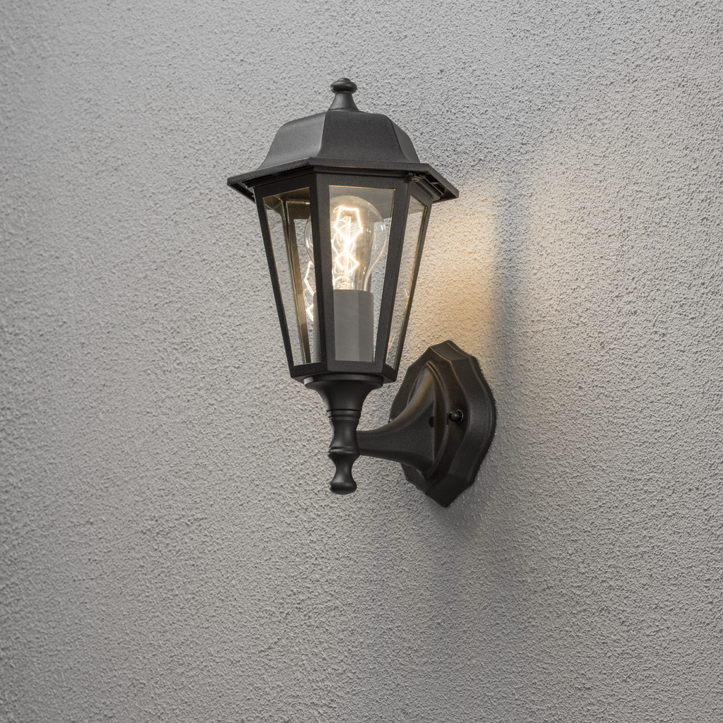 Vägglykta Negro lámpara de exterior De Konstsmide - Con su diseño en forma de linterna y paneles de vidrio transparente, la lámpara emite una luz cálida y acogedora que es perfecta para entradas, patios y pasillos.