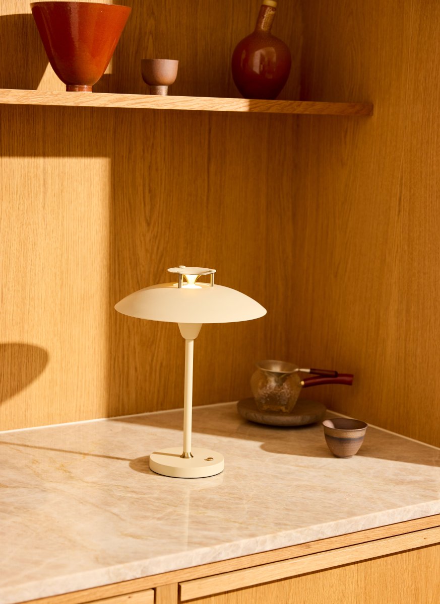 Stepp One-Two -Three 30cm Crema portátil De Halo Design - Esta lámpara de mesa portátil de metal de color crema con elegantes detalles de latón combina estilo y funcionalidad.