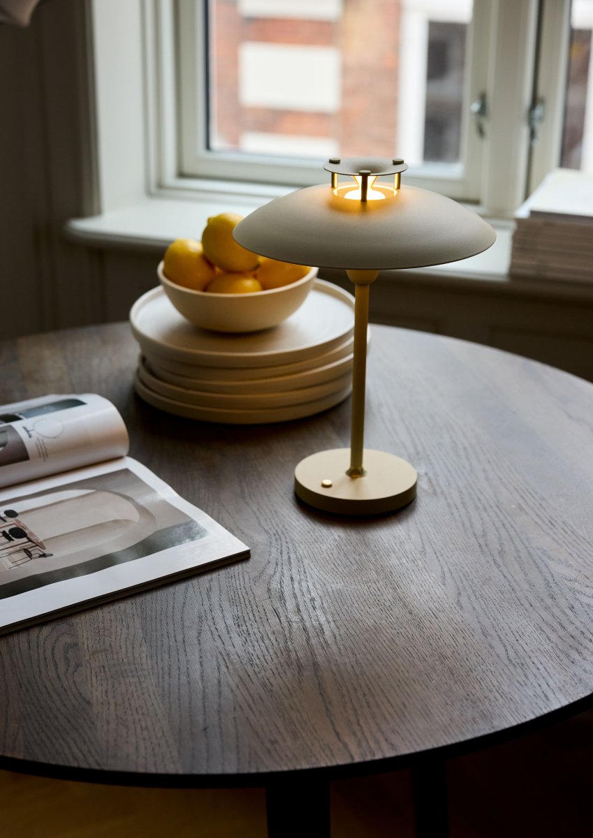 Stepp One-Two -Three 30cm Crema portátil De Halo Design - Esta lámpara de mesa portátil de metal de color crema con elegantes detalles de latón combina estilo y funcionalidad.