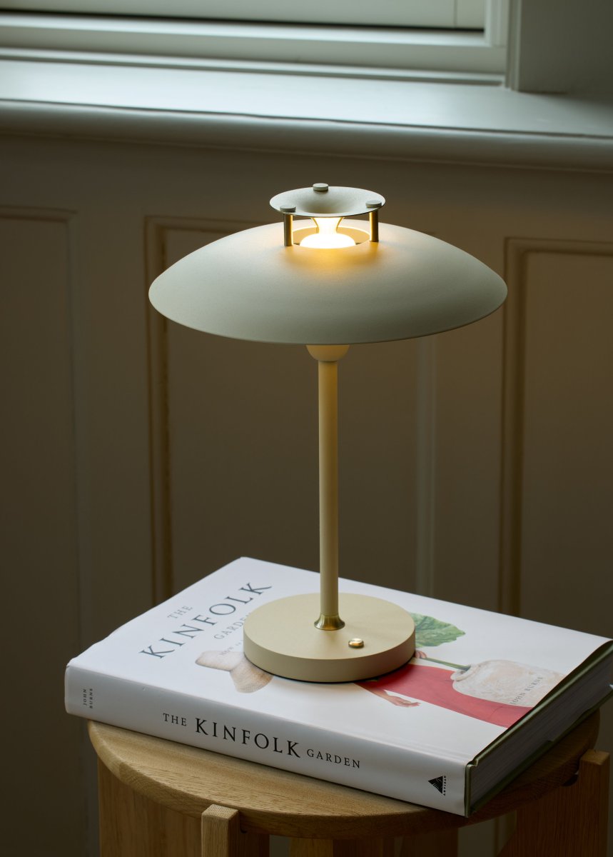 Stepp One-Two -Three 30cm Crema portátil De Halo Design - Esta lámpara de mesa portátil de metal de color crema con elegantes detalles de latón combina estilo y funcionalidad.