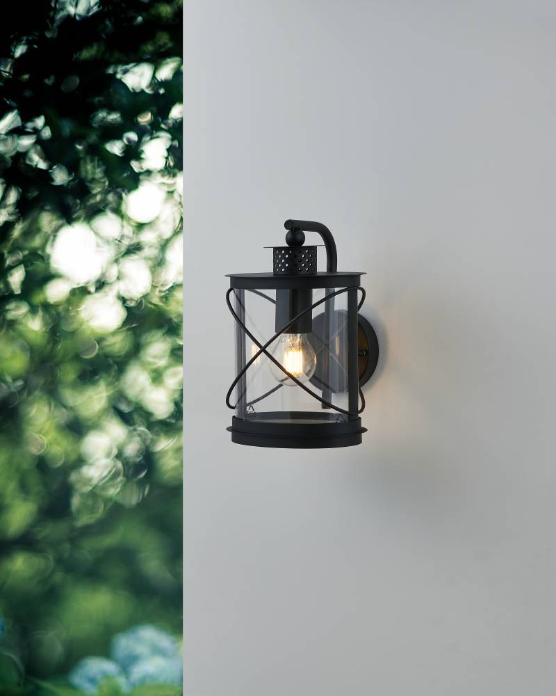 Hilburn Negro lámpara de exterior De Eglo - Esta lámpara de pared tiene un diseño clásico de linterna que combina un marco negro robusto con vidrio transparente, lo que la hace ideal para la iluminación exterior.