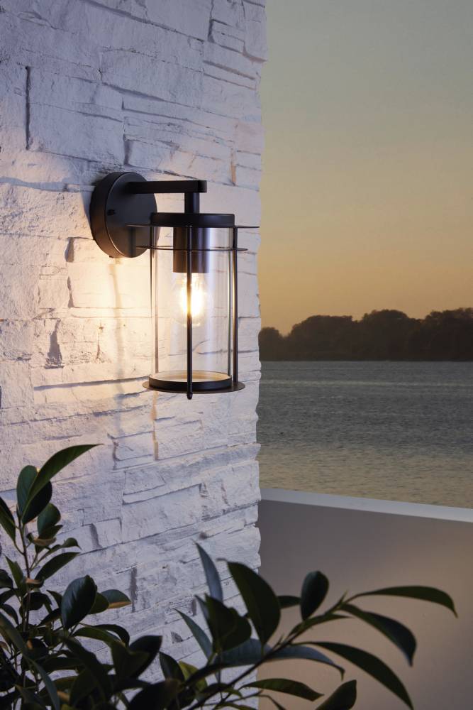 Valdeo Negro lámpara de exterior De Eglo - La l&aacute;mpara presenta un elegante marco de acero galvanizado negro y un cilindro de vidrio transparente que rodea la fuente de luz, proporcionando una iluminaci&oacute;n agradable y acogedora.