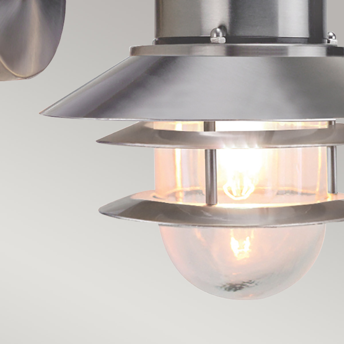 Copenhagen Ø22 acero cepillado lámpara de exterior De Elstead Lighting - Tillverkad av rostfritt st&aring;l i borstad finish och glas, erbjuder den en h&aring;llbar och v&auml;dert&aring;lig konstruktion som passar perfekt f&ouml;r fasader, entr&eacute;er och uteplatser.