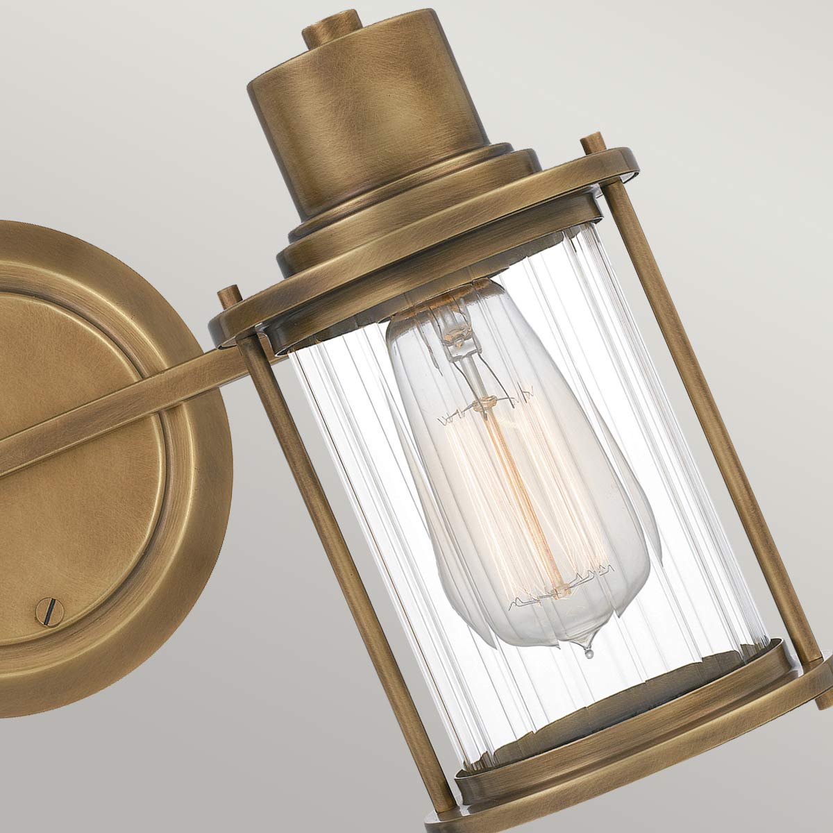Riggs 38cm Latón crudo lámpara de baño De Elstead Lighting - La lámpara de pared Riggs, fabricada en cristal sin marco, combina un diseño industrial ligero con detalles elegantes como el cristal transparente acanalado.